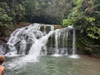 a person standing in front of a waterfall at La Ceiba Ecoadventures Refugio de vida silvestre in Platanillo