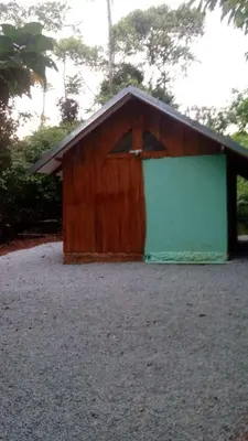 a brown and green building with trees in the background at La Ceiba Ecoadventures Refugio de vida silvestre in Platanillo