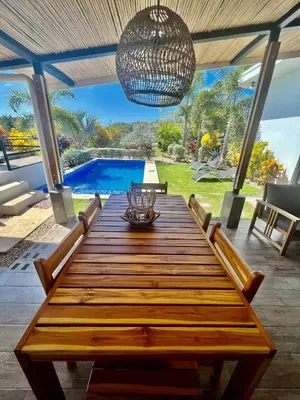 a wooden table with chairs and a chandelier at Casa Bella 3 Bdrm House w Pool in Gated Community in Cuajiniquil
