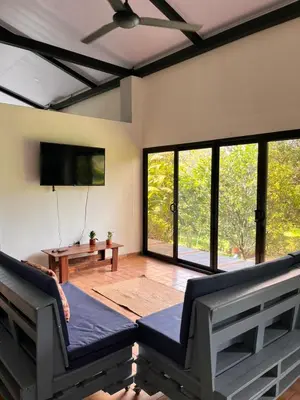 a living room with a couch and a flat screen tv at Casa Rural Los Almendros - Tarcoles in Capulín