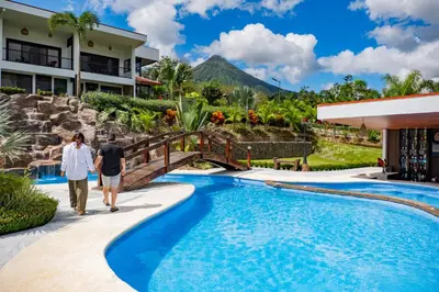 a man and a woman walking by a swimming pool at Hotel Sanctuarium in Fortuna