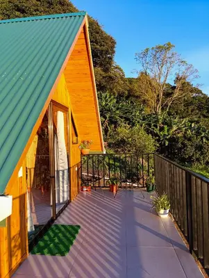 a house with a green roof and a deck at Cabaña El Trogon in Monteverde Costa Rica