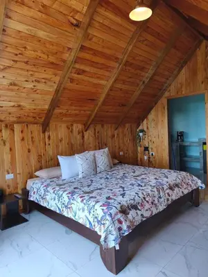 a bed in a room with a wooden ceiling at Cabaña El Trogon in Monteverde Costa Rica