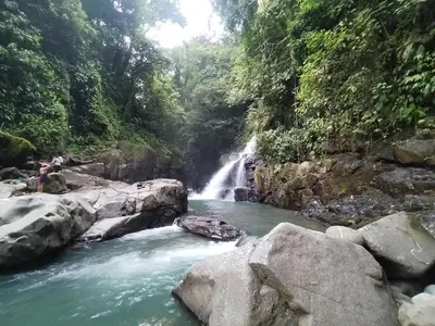 a waterfall in the middle of a river with rocks at Wildlife Reserve La Ceiba Ecoadventures in Platanillo