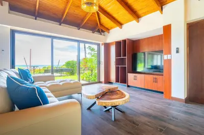 a living room with a couch and a table and a tv at NEW-Gated-Panoramic sunset ocean view-pool-4 suite in Ojochal