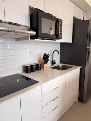 a white kitchen with a microwave and a sink at Spectacular view and comfort from the 21st floor in San José