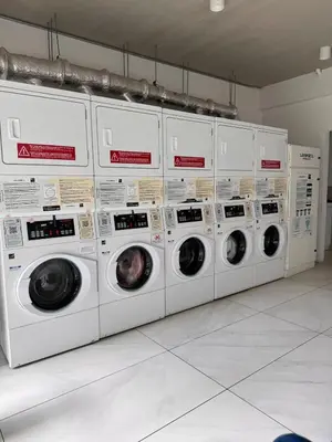 a row of washers and dryers in a laundry room at Spectacular view and comfort from the 21st floor in San José