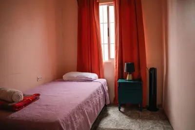 a bedroom with a bed and a window with red curtains at 5-minute walk downtown apartment in Fortuna