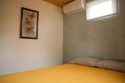 a bedroom with a yellow bed and a window at 5-minute walk downtown apartment in Fortuna