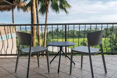 two chairs and a table on a balcony with palm trees at Villa Marala in Esterillos