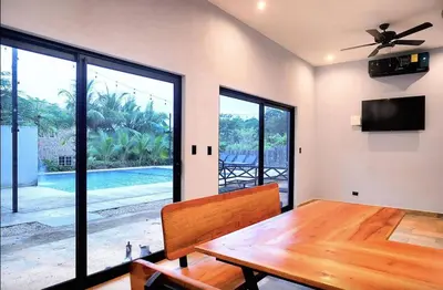 a dining room with a wooden table and a tv at El Castillo Casa Azul in Cuajiniquil