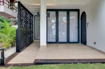 an entrance to a house with black doors and a wooden porch at Seaside Hideaway Walk to Playa Flamingo Marina in Playa Flamingo