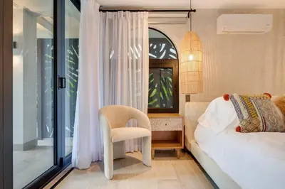 a bedroom with a bed and a chair and a window at Seaside Hideaway Walk to Playa Flamingo Marina in Playa Flamingo