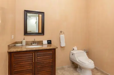 a bathroom with a toilet and a sink and a mirror at Matapalo 202-Poolside Condo at Tamarindo in Tamarindo
