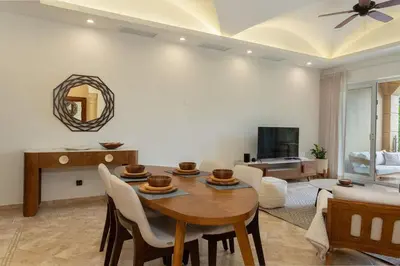 a living room with a table and chairs and a tv at Matapalo 202-Poolside Condo at Tamarindo in Tamarindo