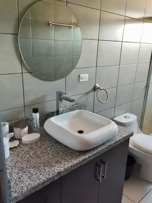 a bathroom with a sink and a toilet and a mirror at Daitares Home in San Pedro