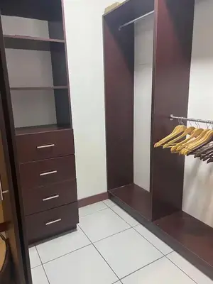 an empty closet with brown cabinets and wooden shelves at Daitares Home in San Pedro