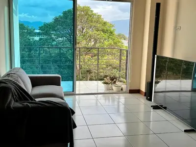 a living room with a couch and a large window at Daitares Home in San Pedro