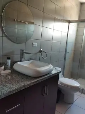 a bathroom with a sink and a toilet and a mirror at Daitares Home in San Pedro