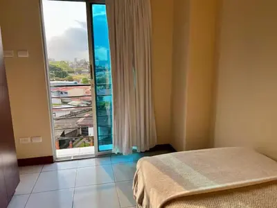 a bedroom with a bed and a large window at Daitares Home in San Pedro
