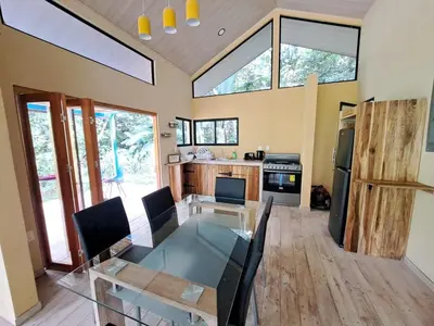 a living room with a glass table and a kitchen at Casa Alma in Platanillo