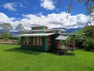 a green house with a porch on a lawn at Casa Hermosa FAM Little House in Santa María