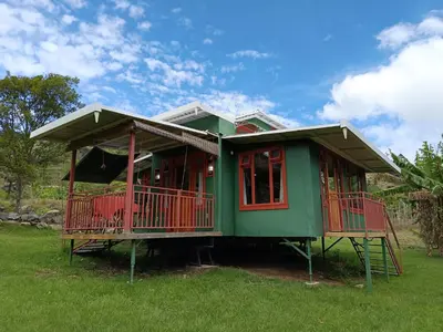 a green house with a red deck in a field at Casa Hermosa FAM Little House in Santa María