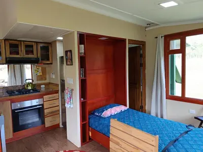 a small bedroom with a bed and a kitchen at Casa Hermosa FAM Little House in Santa María