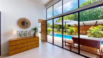 a living room with a large window and a pool at Casa Luna Rosa in Uvita