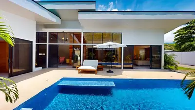a house with a swimming pool and an umbrella at Casa Luna Rosa in Uvita