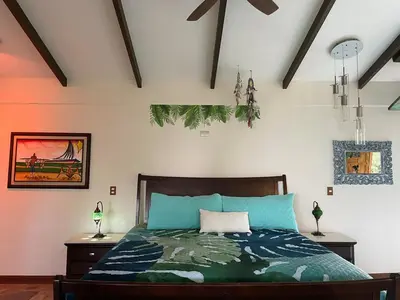 a bedroom with a bed with a green comforter at Casa Bali in San Francisco de Palmera