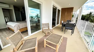a porch with chairs and a bed and a table at Pacific Point - Pure Vida in Jaco, Costa Rica in Jacó
