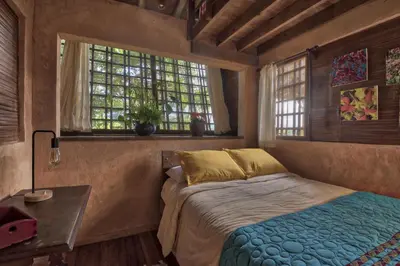 a bedroom with a bed and a table and windows at Casa Alma, Nature Escape with River, Trails and Views