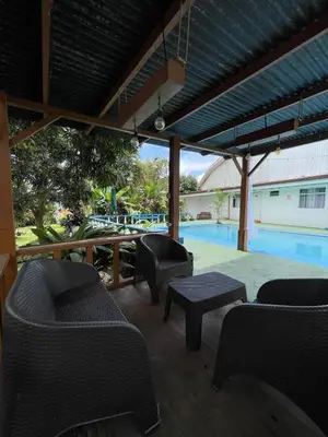 a patio with chairs and a table and a pool at Hotel Geliwa in Turrialba