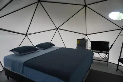 a bedroom with a tent with a bed and a television at Osaglamping in Palmar Norte