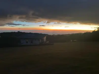 a house in a field with the sunset in the background at Casa Dalia in Monteverde Costa Rica