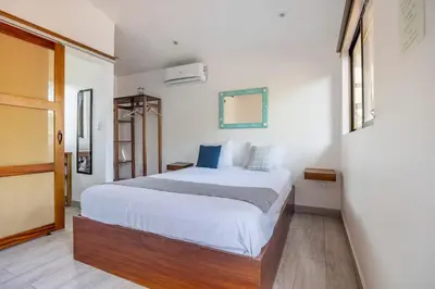 a bedroom with a bed with white sheets and blue pillows at La Buena vida Cabina 2 in Refundores