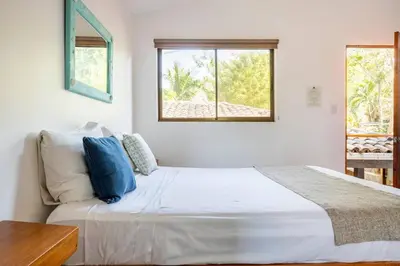 a bedroom with a large white bed with blue pillows at La Buena vida Cabina 2 in Refundores