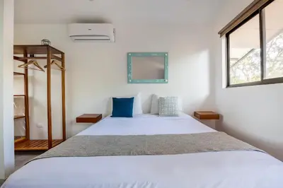 a bedroom with a large white bed with blue pillows at La Buena vida Cabina 2 in Refundores