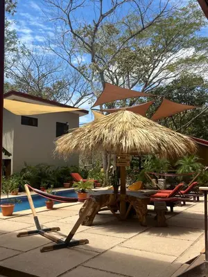 a table with a straw umbrella and chairs next to a pool at Tekana Boutique Jungle Retreat in Tamarindo