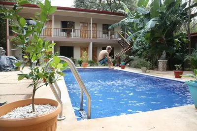 a man is standing next to a swimming pool at Tekana Boutique Jungle Retreat in Tamarindo