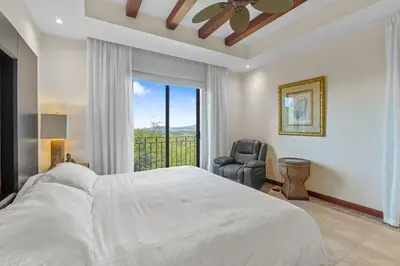 a bedroom with a bed and a chair and a window at Treetop Ocean View Penthouse - Jobo 15 in Playa Conchal
