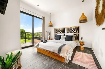 a bedroom with a bed and a large window at TH5 Peaceful Surf Retreat Walk to Beach and Town in Tamarindo