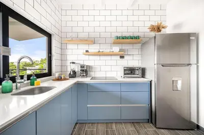 a kitchen with blue cabinets and a stainless steel refrigerator at TH5 Peaceful Surf Retreat Walk to Beach and Town in Tamarindo