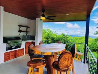 a kitchen with a wooden table on a balcony at Casa Colibri Tropical Ocean View 5 min to Beach in Nicoya
