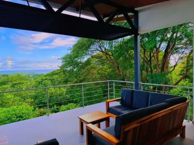 a balcony with a couch and a view of the ocean at Casa Colibri Tropical Ocean View 5 min to Beach in Nicoya