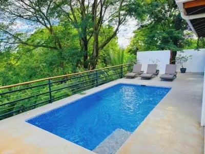 a swimming pool with lounge chairs next to a fence at Casa Colibri Tropical Ocean View 5 min to Beach in Nicoya