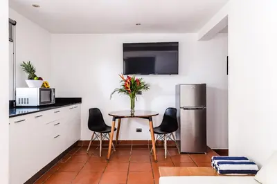 a kitchen with a table with chairs and a refrigerator at Hotel Gardenia Tamarindo in Tamarindo