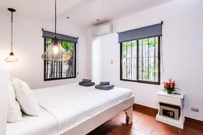 a white bedroom with a bed and two windows at Hotel Gardenia Tamarindo in Tamarindo