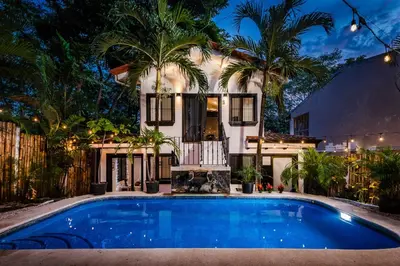 a pool in front of a house with palm trees at Hotel Gardenia Tamarindo in Tamarindo